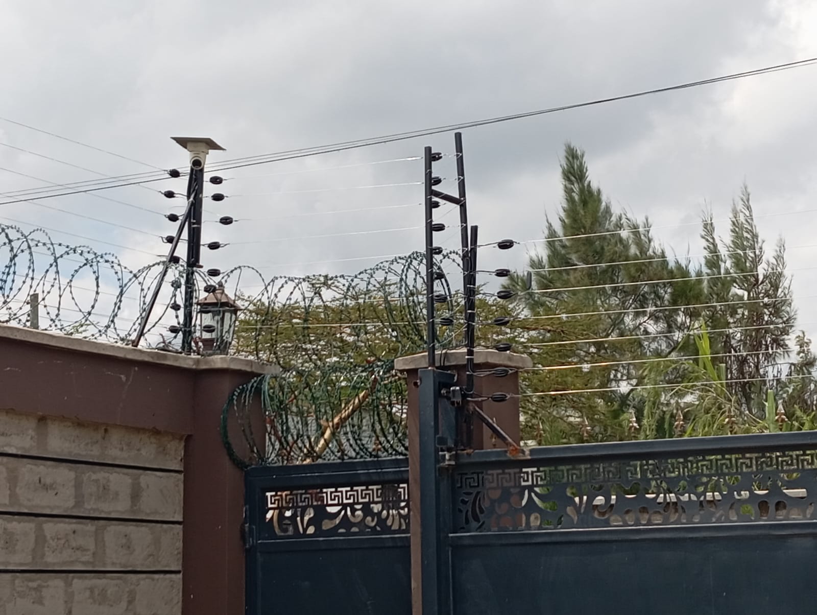 Electric fence, CCTV camera and razor wire on perimeter wall and gate